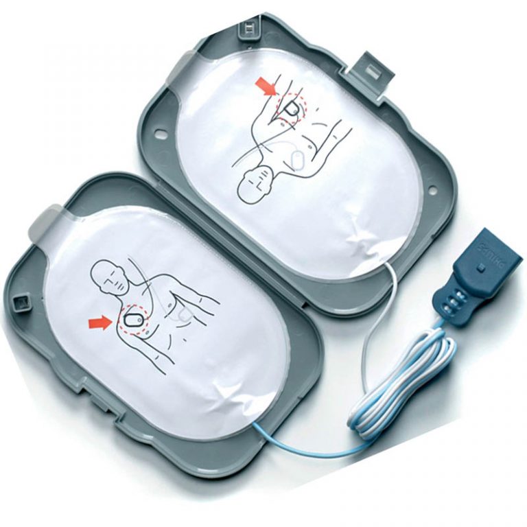 Uppvikt grå plastförpackning med två kablar och vita skyddsfilmer, illustrerade med en man som visar var elektroderna ska placeras.